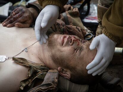 A military medic give first aid to a wounded soldier on the road near Bakhmut, Donetsk region, Ukraine, Thursday, May 11, 2023.