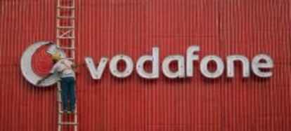un trabajador arregla un cartel de Vodafone