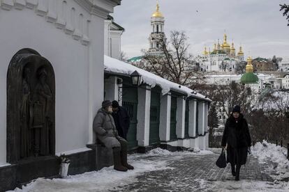 Dos peregrinos descansan en los aledaños del monasterio de las Cuevas, en Kiev. Al fondo pueden verse las torres y las cúpulas de la catedral.