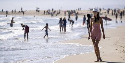 Una turista con mascarrilla pasea por una playa en Los Angeles (California)
