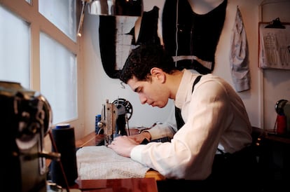 El joven sastre cose a máquina en su estudio.