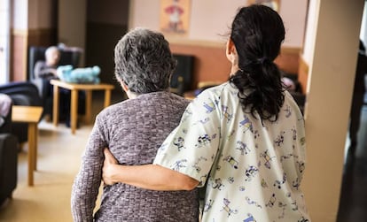 Una cuidadora ayuda a una mujer en una residencia de ancianos. 