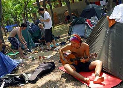 Un joven asistente al festival de Benicàssim entretiene la espera tocando la guitarra.