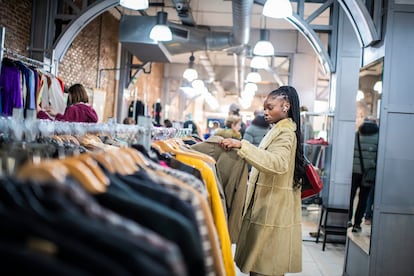 Una mujer busca ropa en una tienda de segunda mano.