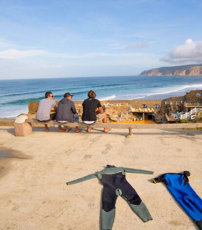 Surfistas en Gincho, con la piscina del hotel Muchaxo al fondo.