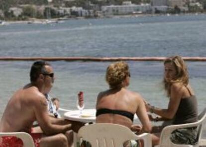 Unos turistas conversan en una terraza en la playa ibicenca de Talamanca. 