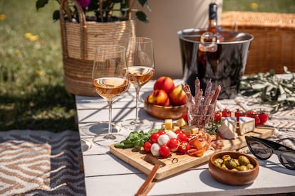 rose wine glasses with antipasti picnic food snacks on sunny garden party table