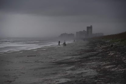 Varias personas en bicicleta en la playa de Atlantic Beach, Florida, a la llegada del huracán Matthew.