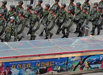 Soldados chinos patrullan en Kangding, en la provincia de Sichuan, junto a una valla publicitaria que anima a hacer turismo en la zona.