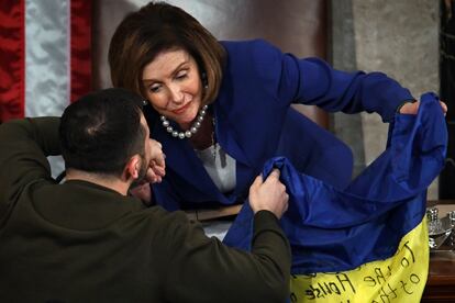 Zelenski intercambia unas palabras con la presidenta del Congreso, Nancy Pelosi, mientras le entrega la bandera de Ucrania.