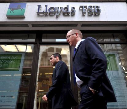 Dos ejecutivos caminan frente a una sucursal del banco Lloyds en Londres.