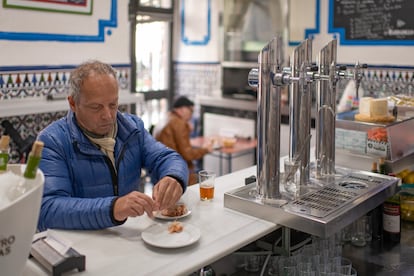 Un hombre toma unos langostinos de aperitivo en la taberna El Boquerón. 