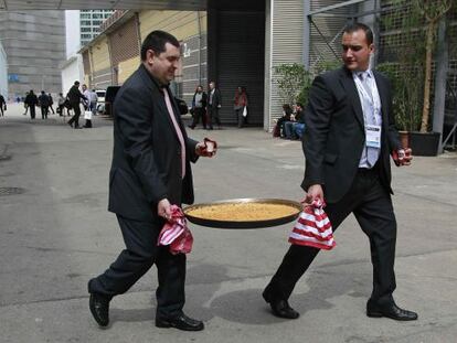 Dos personas sacan una paella recién elaborada del pabellón multiproducto, durante la tercera jornada del salón Alimentaria.