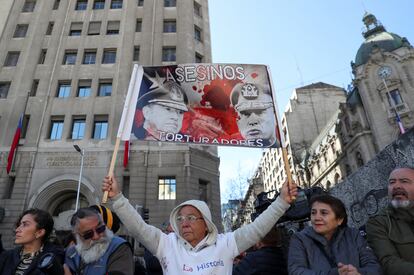 Un hombre sostiene una pancarta con imágenes de los militares que encabezaron el golpe de Estado y las palabras "asesinos" y "torturadores", durante la ceremonia de este lunes.