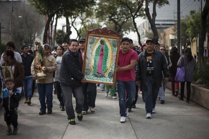 Un grupo de personas se turnan para cargar una imagen de la Virgen mientras se dirigen hacia el templo