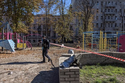 Un agente de policía patrullaba el lunes una zona cercana a un parque infantil dañado tras los ataques rusos al centro de Kiev.