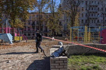 Un agente de policía patrullaba el lunes una zona cercana a un parque infantil dañado tras los ataques rusos al centro de Kiev.