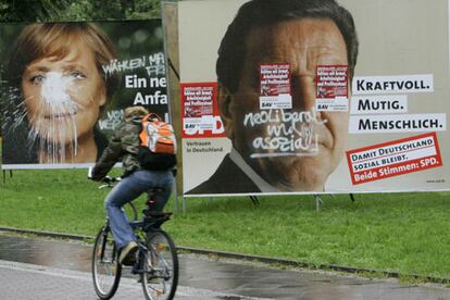 Un ciclista pasa por delante de carteles electorales de los candidatos Schröder y Merkel en Berlín.