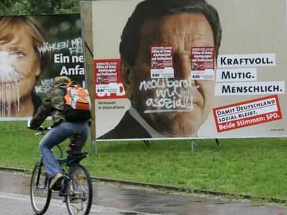 Un ciclista pasa por delante de carteles electorales de los candidatos Schröder y Merkel en Berlín.