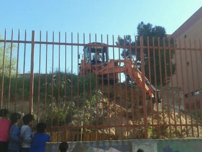 Alumnos del centro observan a la excavadora que destruyó el huerto.
