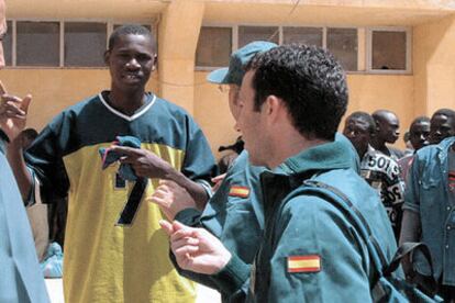 Guardias civiles conversan con un subsahariano en el cuartel de la Gendarmería marroquí en El Aaiún.