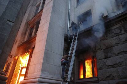 Las personas que se encontraban en el interior del edificio cuando se ha declarado el incendio esperan a ser rescatadas en las cornisas de las ventanas. 30 ciudadanos han muerto por intoxicación de monóxido de carbono y otros ocho al saltar por las ventanas del edificio cuando intentaban escapar de las llamas.