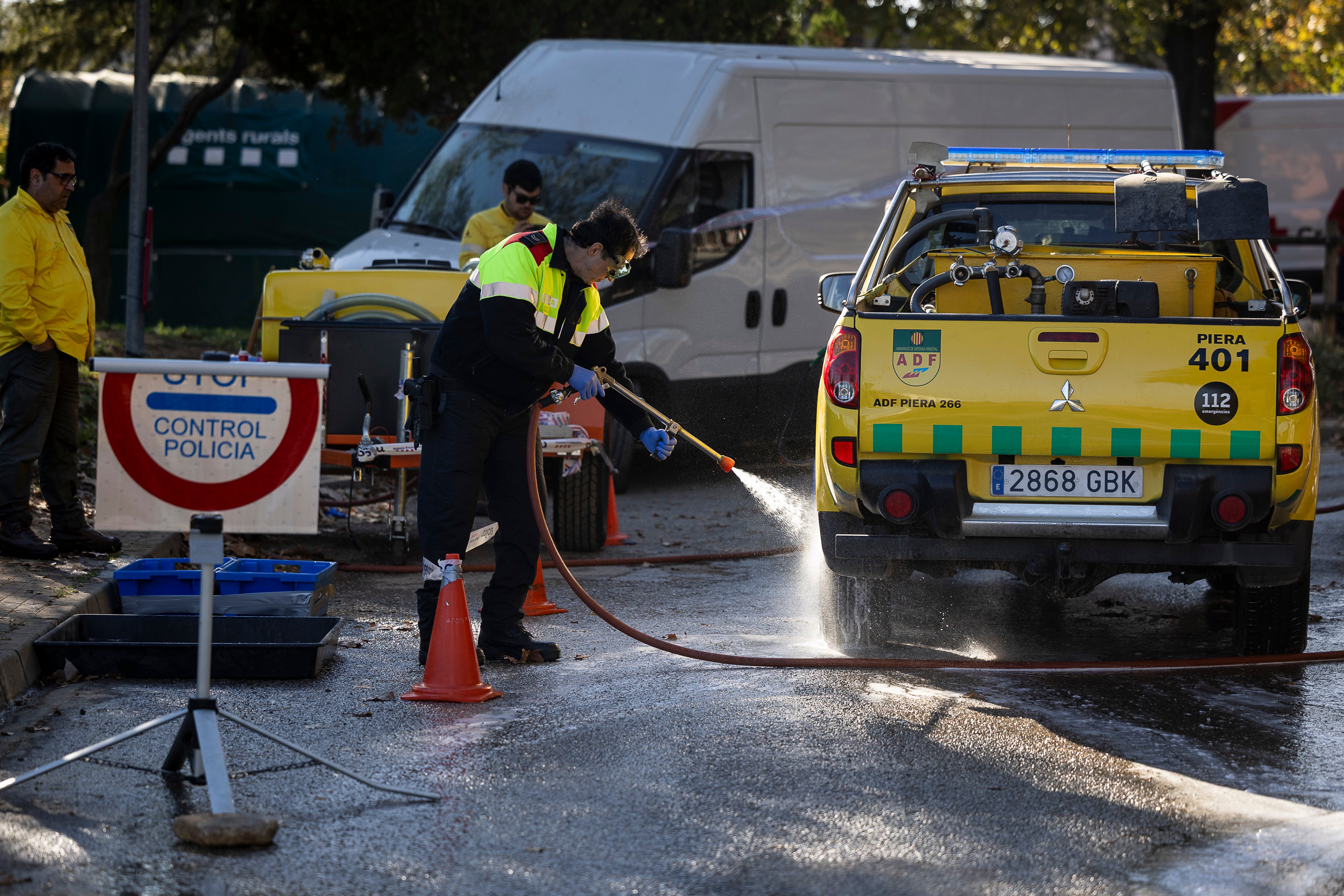 Un agente de los Mossos d'Esquadra desinfecta un vehículo de las Agrupacions e de Defensa Forestal (ADF) que han trabajado en la zona con presencia de peste porcina.