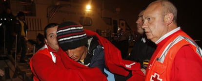 Uno de los inmigrantes es arropado por voluntarios de la Cruz Roja en el puerto de Almería.
