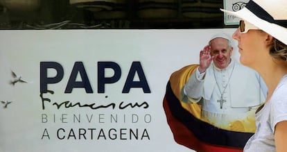 Una mujer camina frente a un cartel con la imagen del papa Francisco en Cartagena.