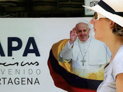 Una mujer camina frente a un cartel con la imagen del papa Francisco en Cartagena.