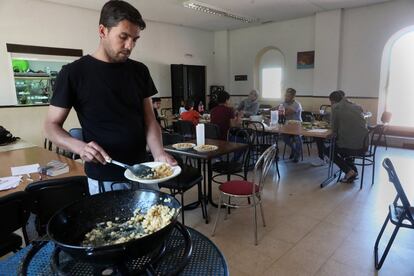 Mahmoud se sirve un plato de comida en el comedor de la parroquia de San Carlos Borromeo, en Vallecas.