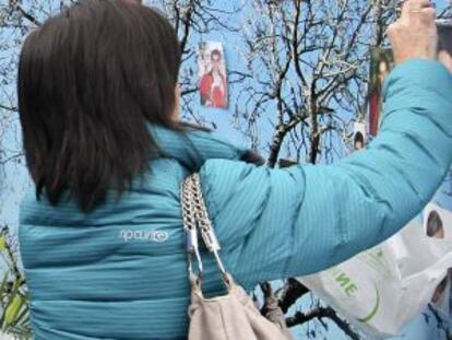 Una mujer pega la foto de un familiar fallecido en accidente de tráfico durante el acto en San Sebastián.