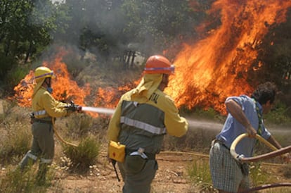 Dos bomberos y un voluntario trabajan en la extinción del incendio en Barco de Ávila.