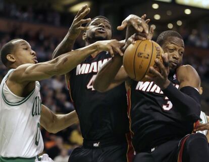 Avery Bradley de los Celtics trata de arrebatar el balón a los jugadores de Miami Udonis Haslem (en el centro) y Dwyane Wade.