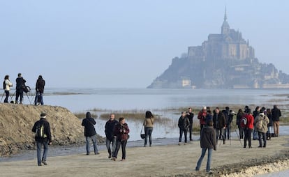 Gente esperando la 'marea del siglo' enfrente del Monte Saint-Michel, en Francia. La inusual alineación del Sol y la Luna, que este viernes produjo un eclipse solar, crea una corriente especialmente fuerte cada 18 años.