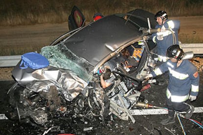 Los bomberos tratan de sacar del amasijo de hierros a uno de los fallecidos en el accidente.