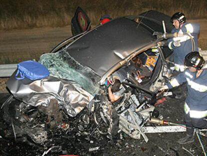Los bomberos tratan de sacar del amasijo de hierros a uno de los fallecidos en el accidente.