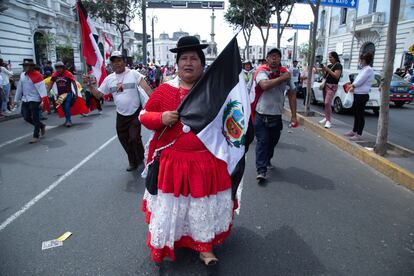Una mujer lleva una de las banderas peruanas con franjas negras en lugar de rojas, indicando el luto por las muertes de manifestantes.