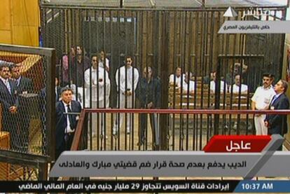 En la jaula de la izquierda, Hosni Mubarak, en camilla; sus hijos Gamal y Alaa, de blanco, y delante de ellos, el exministro del Interior El Adly, en una imagen de la televisión egipcia.