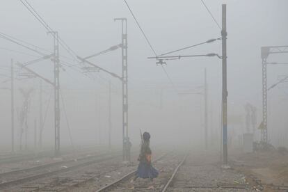 Un 'nihang', o miembro tradicional del ejército sij, cruza las vías del tren entre una densa niebla de contaminación cerca de la estación de tren de  Amritsar (India).
