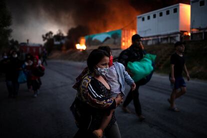 Una mujer carga con su bebé en brazos mientras huye de las llamas del segundo incendio.