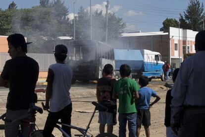 Um grupo de pessoas olha um ônibus de passageiros incendiado, depois de as chamas terem sido apagadas pelos bombeiros em Guadalajara.