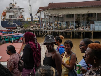 La gente espera en el mercado Stabroek para cruzar el río Demerara en ferry, cerca de un barco portacontenedores en Georgetown, (Guyana)
