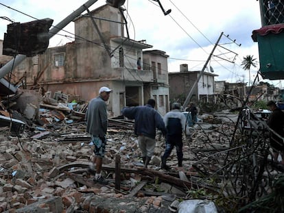 Vários residentes caminham entre os escrombros causados pelo tornado, em Havana.