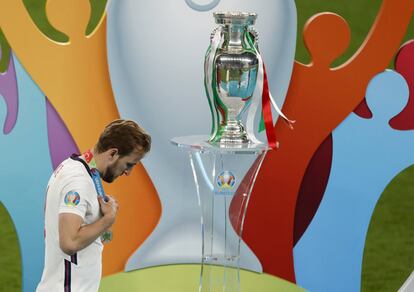 El jugador inglés Harry Kane pasa por delante de la copa tras recibir su medalla de subcampeón después de su derrota ante Italia en la tanda de penaltis de la final del campeonato de Europa de selecciones 2020 en el estadio de Wembley, Londres, el domingo 11 de julio de 2021.