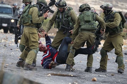 Soldados israelíes detienen a un palestino herido que había tirado piedras después de que miembros de las fuerzas de seguridad israelíes infiltrados dispararan a los manifestantes durante enfrentamientos en Beit El, a las afueras de la ciudad de Ramala.