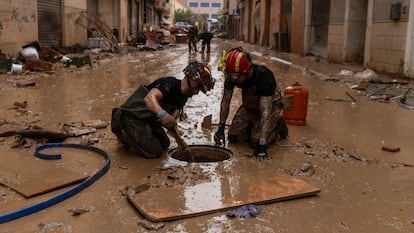 Dos miembros de la Unidad Militar de Emergencias (UME) despejan una alcantarilla en Alfafar (Valencia).