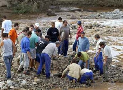 Vecinos de Sabiote (Jaén) inspeccionan restos del todoterreno en el que viajaban los dos desaparecidos.