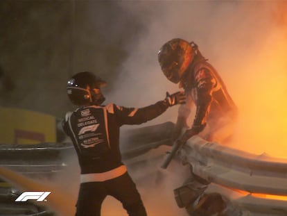 Una persona ayuda al piloto a salir del coche tras el accidente en el Gran Premio de Bahréin.