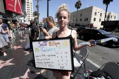 Una joven vende gafas para ver el eclipse el 21 de agosto en Hollywood, California.